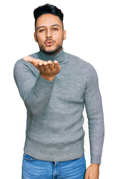 Young arab man wearing casual clothes looking at the camera blowing a kiss with hand on air being lovely and sexy. love expression.