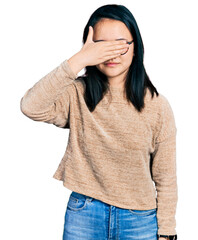 Fototapeta premium Young chinese woman wearing casual sweater and glasses covering eyes with hand, looking serious and sad. sightless, hiding and rejection concept