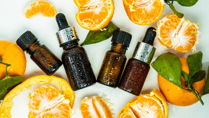 Fragrant tangerine oil with tangerines on a white background. Bottles of citrus essential oil and...
