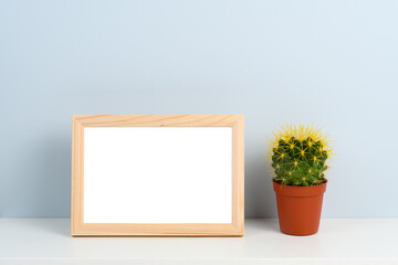 Wooden photo frame and cactus on shelf