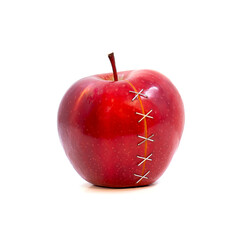 The cut apple is fastened with metal clips on white background