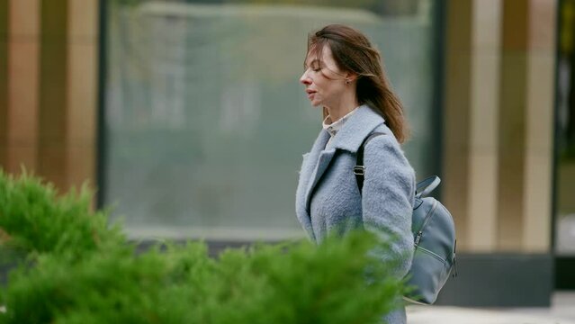 mid age woman walking down city street in autumn or spring day, medium side view portrait