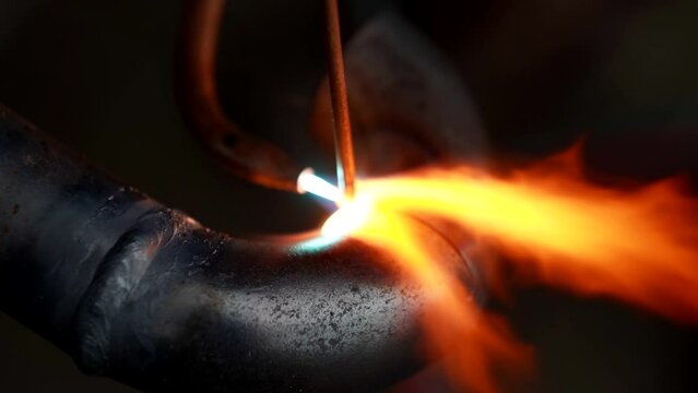 welding of metal pipes in industrial plant, closeup view, red hot metal and fire from gas torch