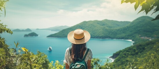 Cheerful young Asian woman travels alone on tropical island mountain peak, enjoying outdoor lifestyle during summer beach vacation. - obrazy, fototapety, plakaty