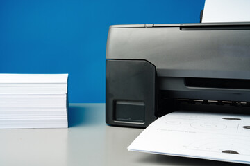 Laser printer on desk against blue background.