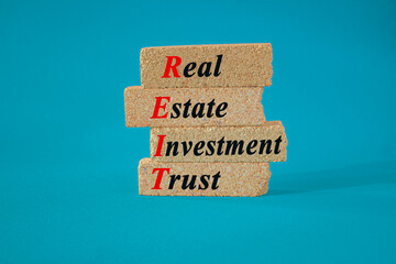 Real estate investment trust symbol. Concept red words Real estate investment trust on brick blocks on beautiful blue background. Business REIT real estate investment trust concept.