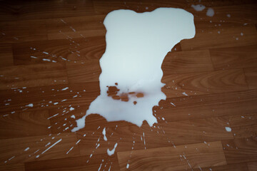 Spilled milk on the floor. White spot of liquid with splashes. Healthy beverage dropped by accident