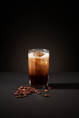 Close-up of a cup of coffee with coffee beans on a mysterious black background. Coffee contains B vitamins and anti-inflammatory agents that can prevent acne caused by dermatitis.