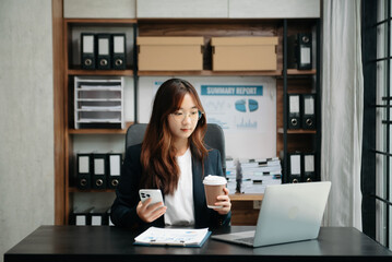  Beautiful Asian business woman typing laptop and tablet Placed at the table at the office.