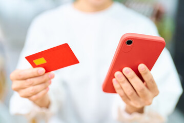 クレジットカードとスマートフォンを持つ女性の手元