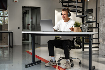 Young man wearing headphones while studying with laptop