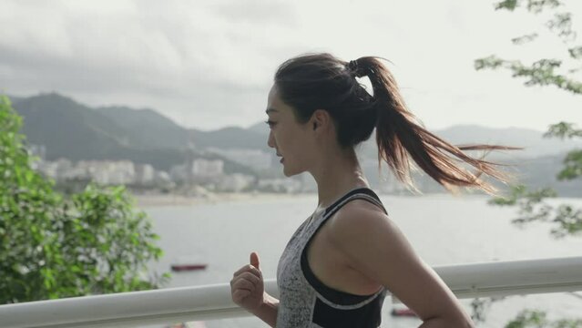 young asian woman female athlete jogging running exercising outdoors on road by the sea