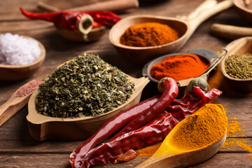 Variety of spices in wooden bowls on old wooden table background.