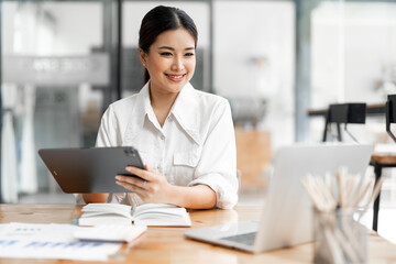 Happy female entrepreneur working on digital tablet in the office
