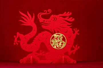 Chinese New Year of Dragon mascot paper cut on red background at horizontal English translation of the Chinese word is fortune and no logo no trademark