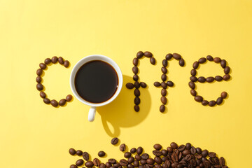 Coffee beans are arranged into the word COFFE with a black coffee cup on a yellow background. Creative images for advertising. Copy space. Coffee theme.