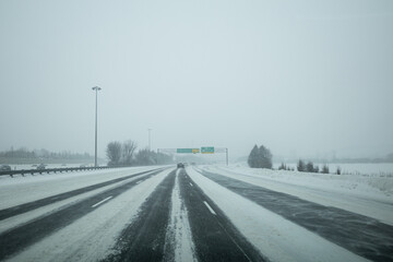 Driving down the highway, visible green signs, during a winters storm in Ottawa, Ontario. Road is...