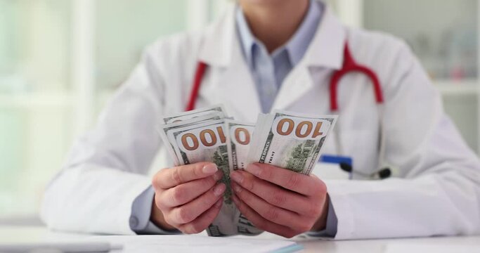 Successful female doctor counts dollar bills earned as salary