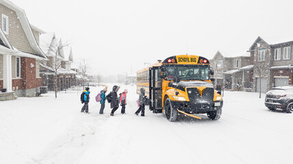 unrecognizable children waiting for bus in snowy neighbourhood during winter - obrazy, fototapety, plakaty