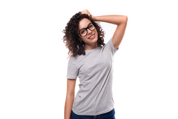 adorable slim curly brunette promoter woman with glasses dressed in gray basic t-shirt with logo...