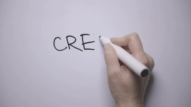 Credit. A woman's hand writes the word CREDIT on a white board with a black marker. And then crosses out the word "Credit"