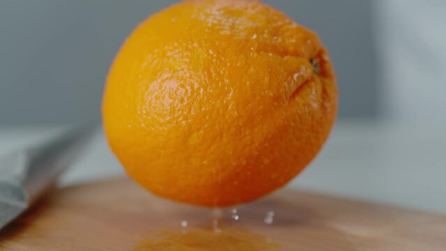 Orange Landing on Cutting Board with Water Droplets Bouncing
