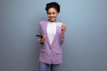 young successful latin woman with afro hair dressed in a lilac jacket shows a mock-up of a bank...