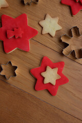 Christmas background with many star shaped shortcrust cookies with red sugar glaze and metallic cookie cutters on a wooden table