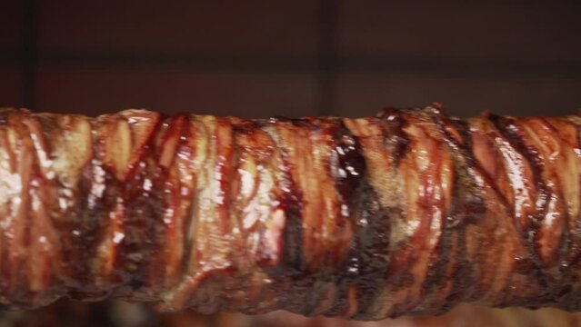 Close up shot of traditional kokoretsi spinning on spit over charcoal traditional easter preparation Pan movement