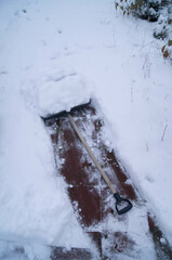 A snow shovel lies on a cleared path, the only interruption in the freshly fallen snow, marking the progress of winter's diligent upkeep and cold-weather labor.