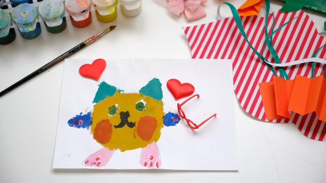 Child painting lovely cat,  hearts, making crafts from paper and plasticine. Handmade concept for birthday, mothers day or Valentines day. Education. Inspiration and imagination