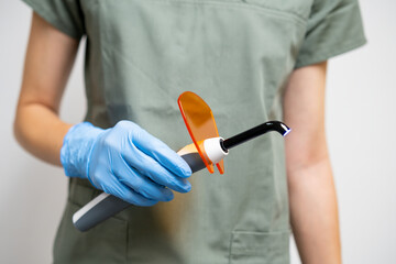 Dental curing light in dentists hand in rubber gloves