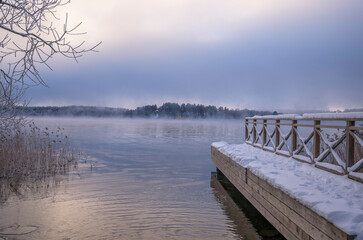 Jetty, smoke, fog, over the lake Mälaren, frost on trees and snow in the Stockholm district Bromma