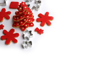 Christmas tree made of star shaped shortcrust cookies with red sugar glaze and cookies and cookie cutters on white background