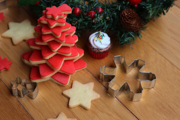 Christmas tree made of star shaped  cookies with red sugar glaze and festive green garland with red berries  on wooden table