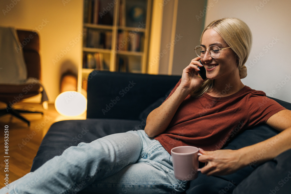 Wall mural Beautiful blond woman having a pleasant phone call from home.