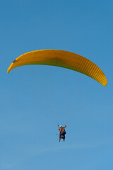 Paragliding in the sky over the sea. The concept of parachute flight. Tandem skydiver pilot and passenger fly on a sunny day.