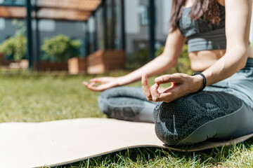 A woman meditates in the lotus position and relaxes in nature in the park in summer sunny weather. Yoga, mental health, relaxation, health concept.