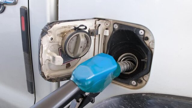 Blue fuel nozzle in the tank refilling this vehicle, gas station in Thailand.