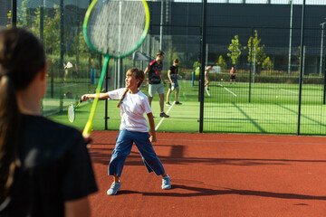 Two girls with badminton rackets on the football field.