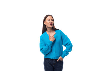 young active caucasian woman with black hair dressed in a blue cardigan and jeans points with her hands to have an idea on a white background