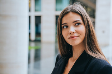 Fototapeta premium Close up portrait of successful young adult woman standing outside looking away, thinking about business, planning agenda. Businesswoman looking for solution. Financial people.