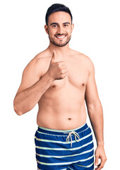 Fototapeta premium Young handsome man wearing swimwear doing happy thumbs up gesture with hand. approving expression looking at the camera showing success.