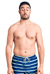 Fototapeta premium Young handsome man wearing swimwear making fish face with lips, crazy and comical gesture. funny expression.