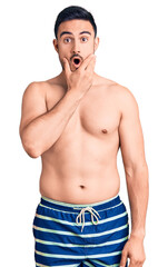 Fototapeta premium Young handsome man wearing swimwear looking fascinated with disbelief, surprise and amazed expression with hands on chin