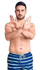Fototapeta premium Young handsome man wearing swimwear rejection expression crossing arms doing negative sign, angry face