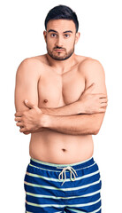 Fototapeta premium Young handsome man wearing swimwear shaking and freezing for winter cold with sad and shock expression on face