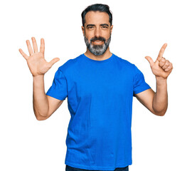 Fototapeta premium Middle aged man with beard wearing casual blue t shirt showing and pointing up with fingers number seven while smiling confident and happy.