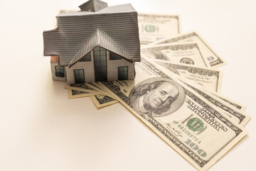 Miniature house model with banknotes on a wooden table, selective focus. Home loan concept.
