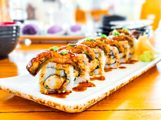 Delicious japanese food and concept. Unagi sushi maki roll with teriyaki sauce on white dish in japanese restaurant.